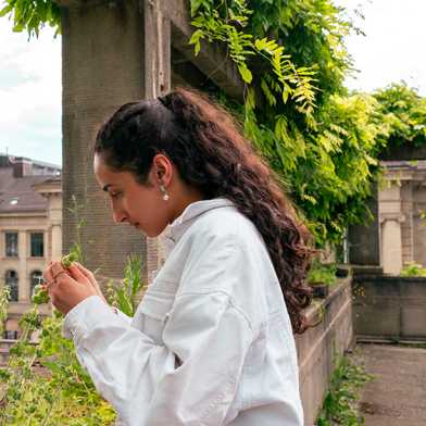 Fatima Ali Ebrahim looking at a plant on the ETH balcony