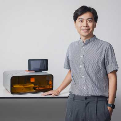 Hao Liu stands in front of the 3D printer he has developed