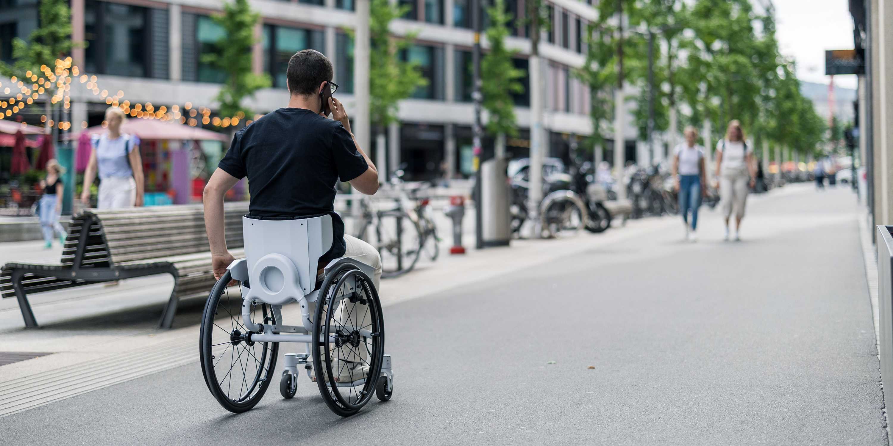 Someone in a wheelchair gives one hand, the other he has on the phone.