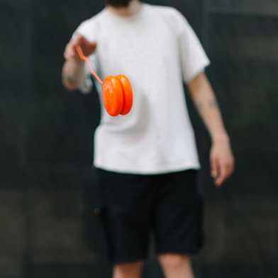 A person in the background swings an orange yoyo, which is in focus