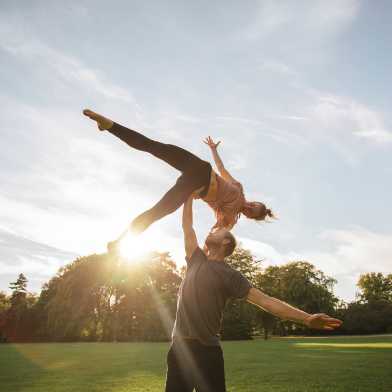 two people doing a lifting acrobatic figure in a meadow