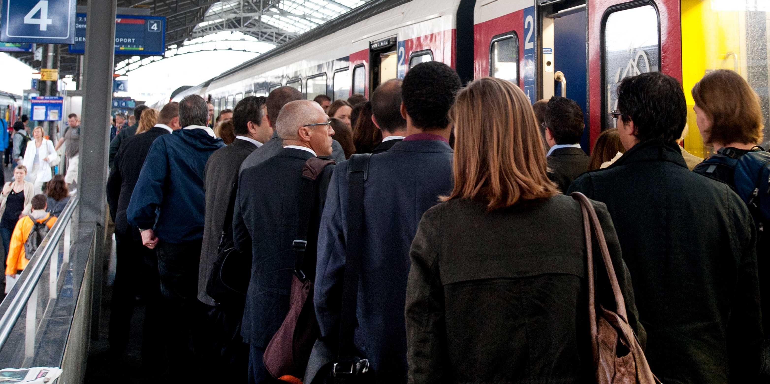 Lots of people at a station, getting on and off a train