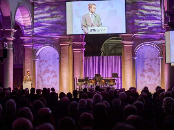 Nic Cantieni stands on the stage in the main building of ETH Zurich and speaks to the audience.