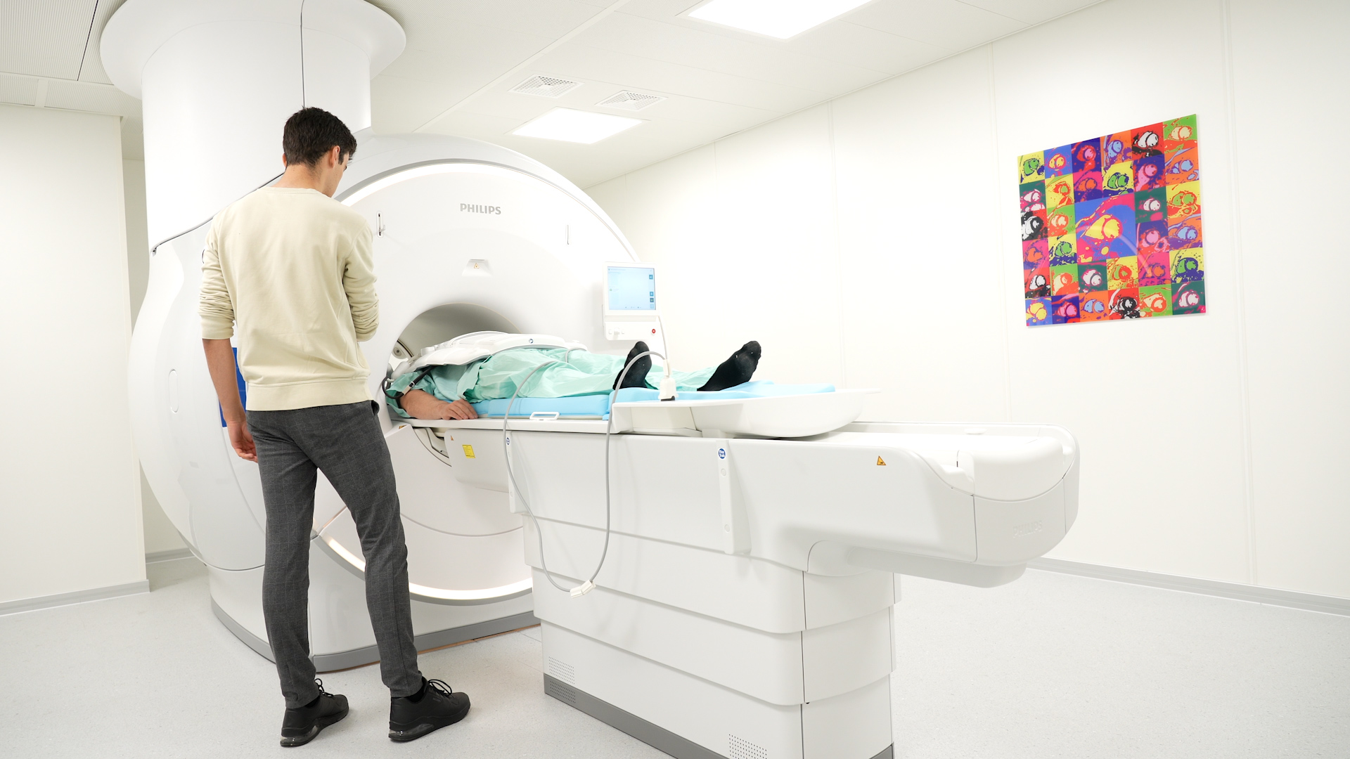 A person is lying in the MRI scanner and is being checked by a researcher.