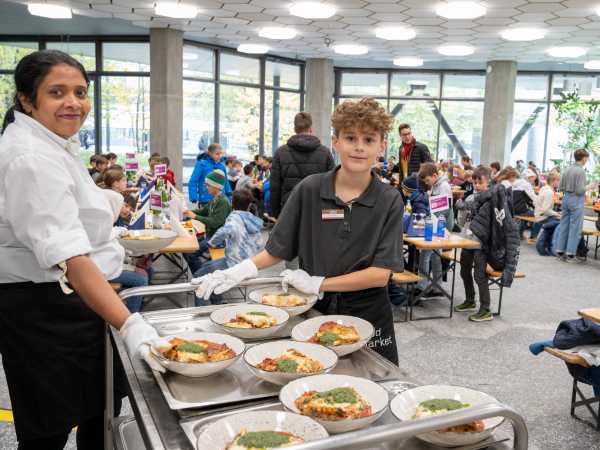 A child helps serving lunch. The boy also participates at the Zukunftstag.