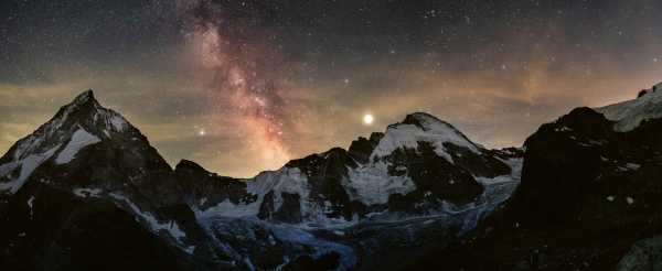 The Milky Way is visible in the night sky behind the silhouette of mountains