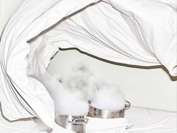 Two steaming cooking pots stand on a bed surrounded by a cloth