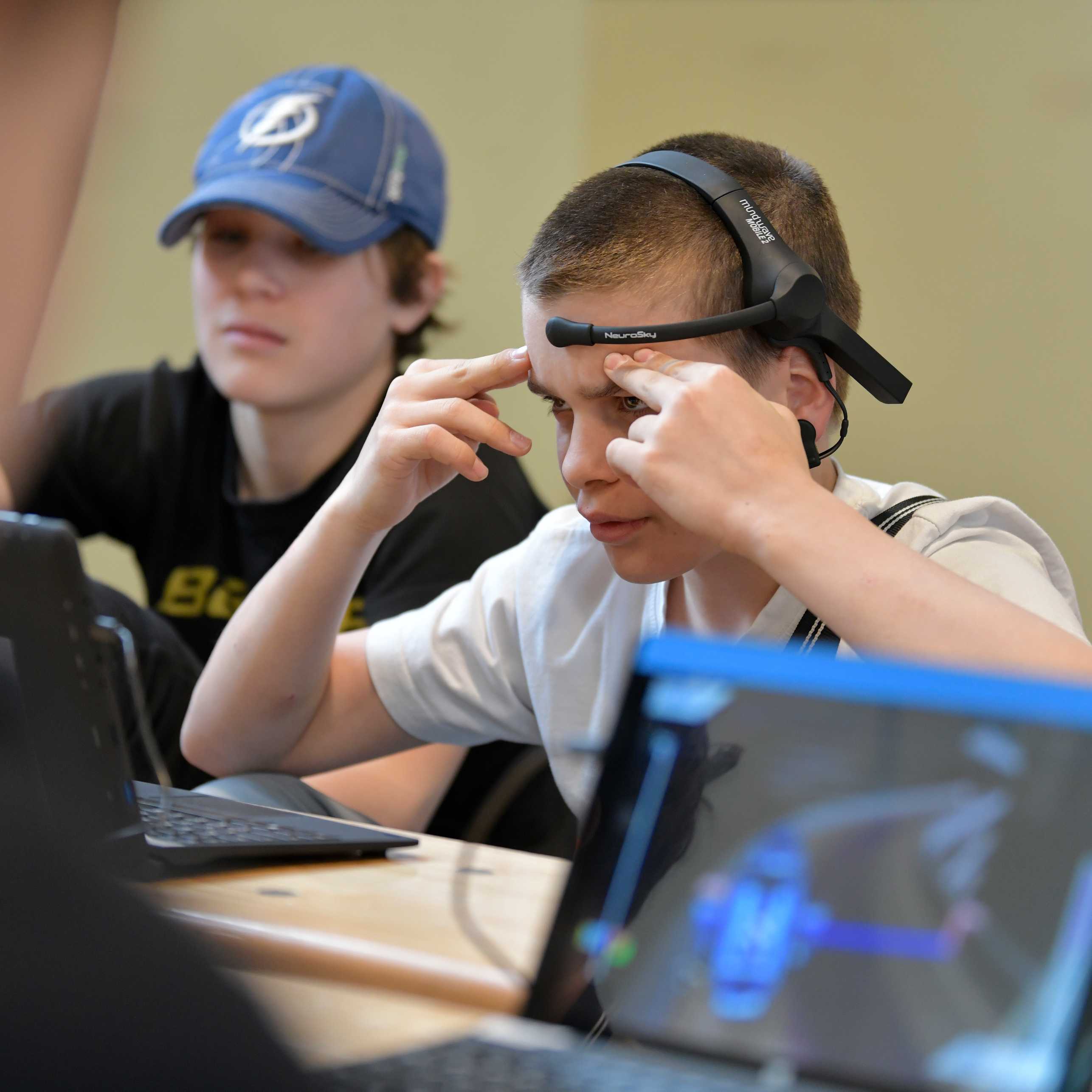 Scholar concentrating, wearing a Brain Comuter Interface (BCI) headset