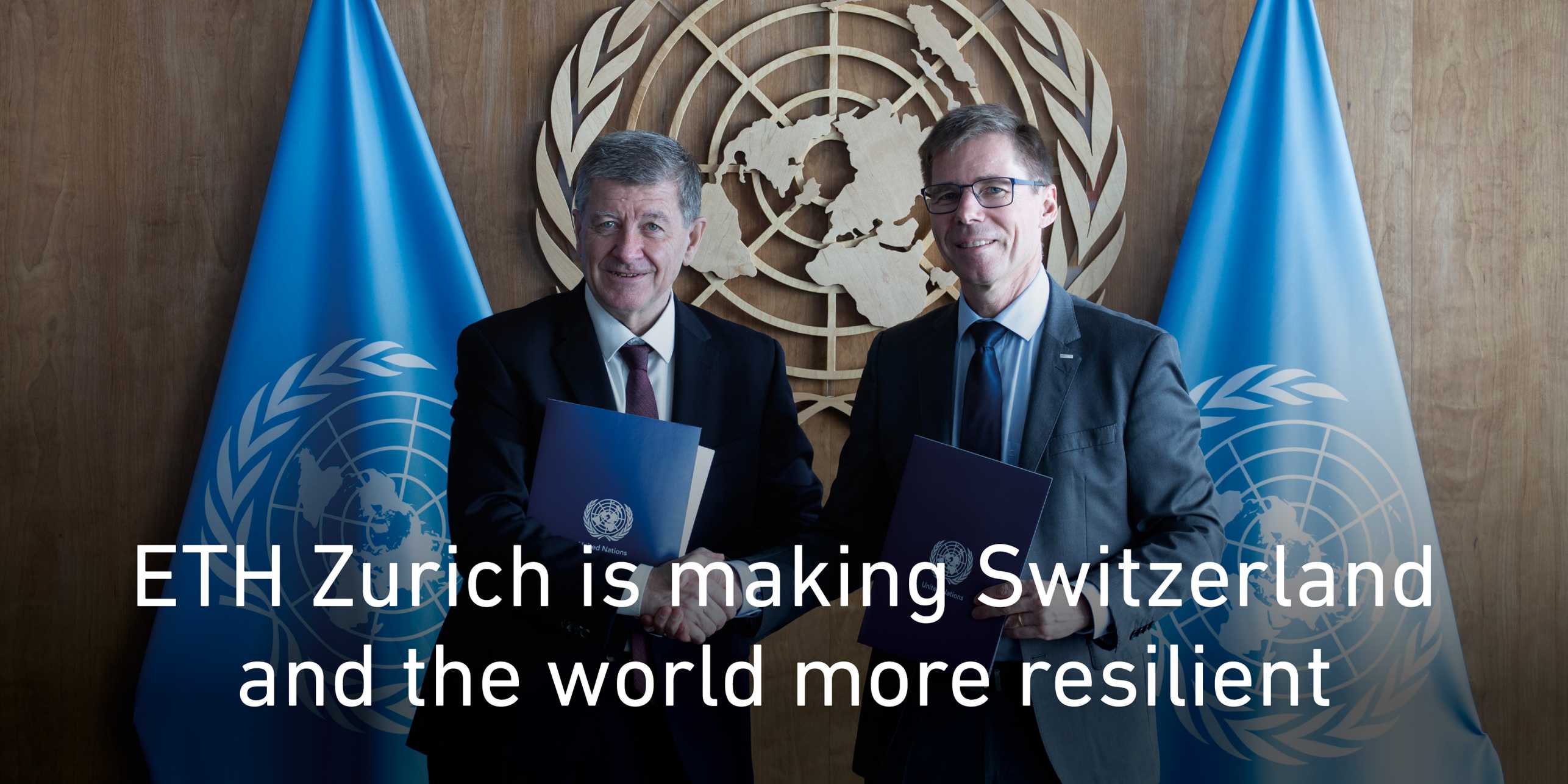 Two men are standing in front of the UN logo and two UN flags and shaking hands. Text: ETH Zurich is making Switzerland and the world more resilient. Link to news article on the partnership with the UN.