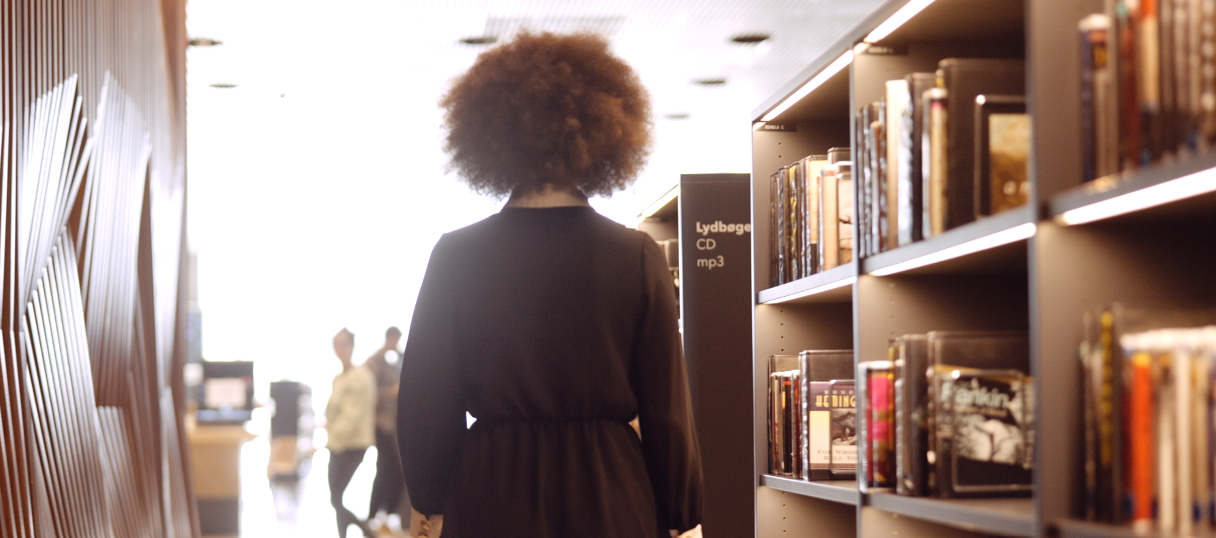 Person läuft entlang von Büchernregalen in einer Bibliothek.