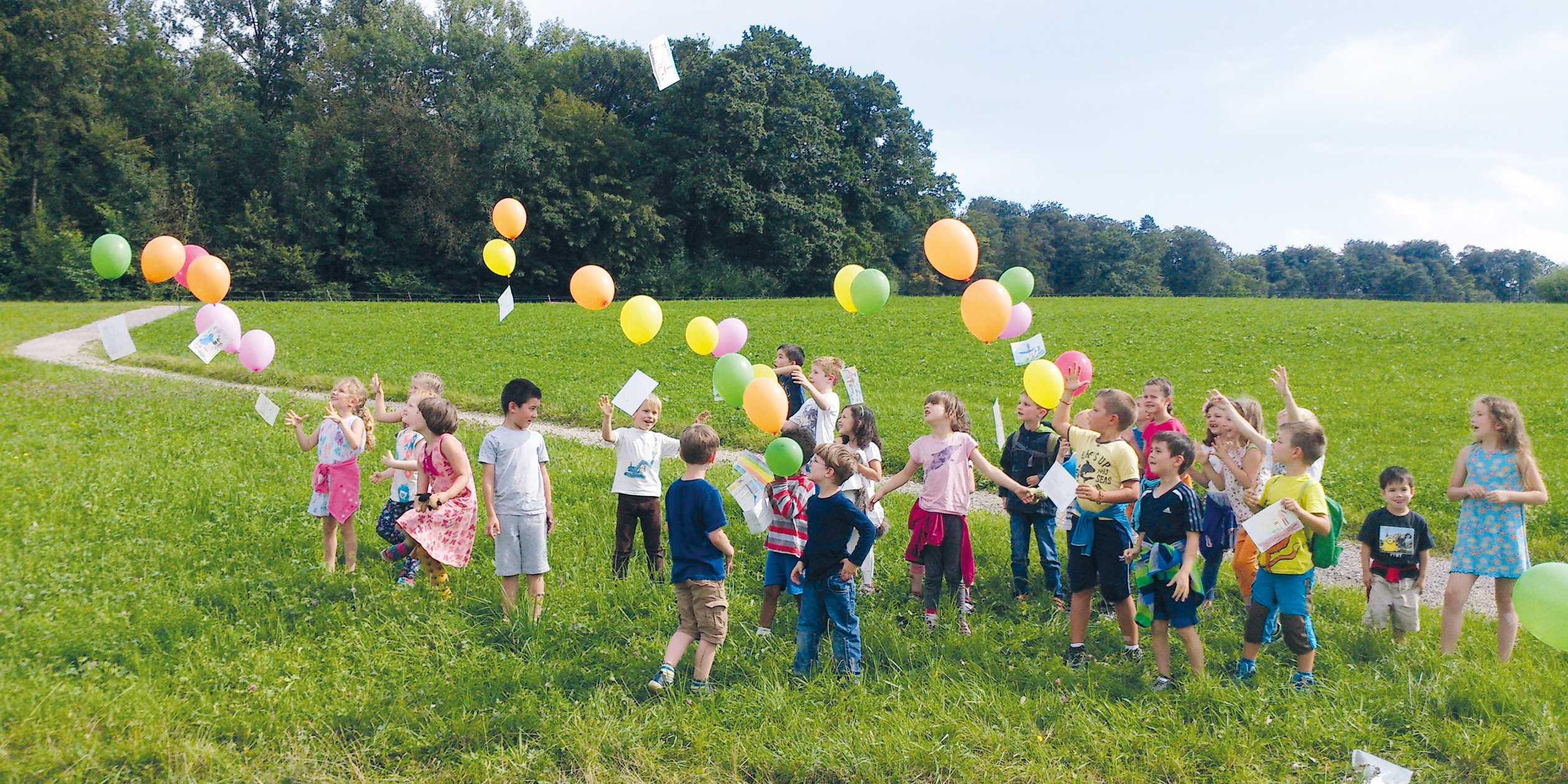 Kinder spielen mit bunten Ballons.