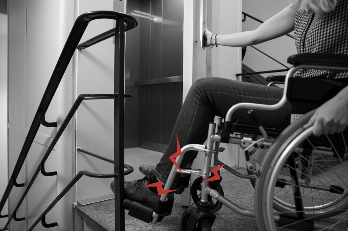 Enlarged view: A person in a wheelchair is unable to open an old lift door because it opens outwards and the wheelchair gets in the way.