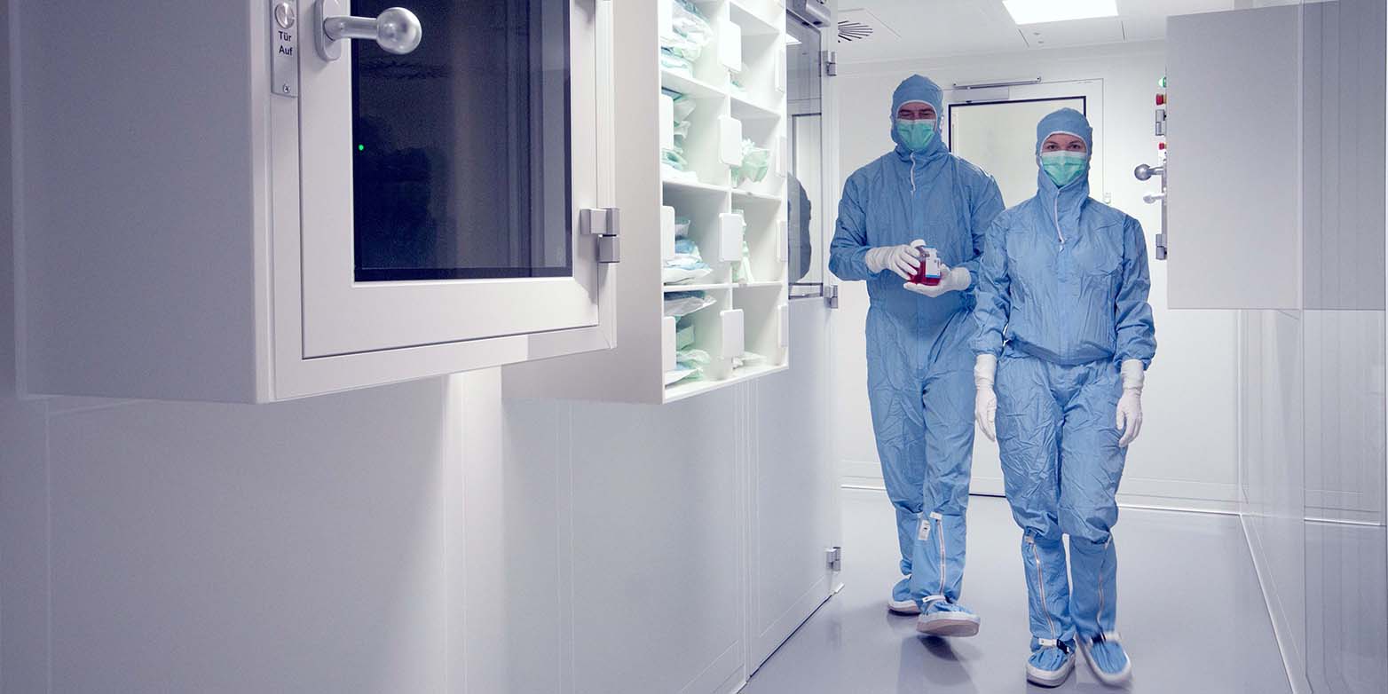 Two regenerative medicine researchers walk through the Wyss Zurich Center in full body suits