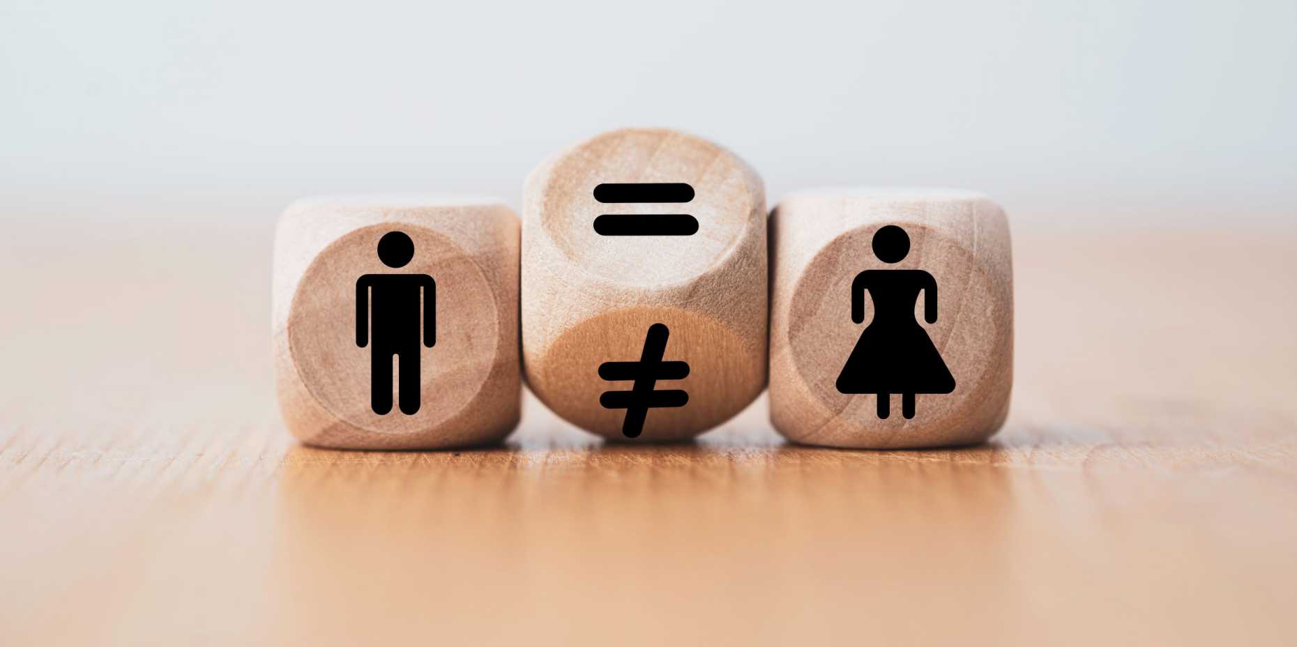 Three dice showing, from left to right, a man, an equal sign and a woman.