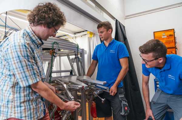 Urs Grob and two apprentices adjust the lifting table