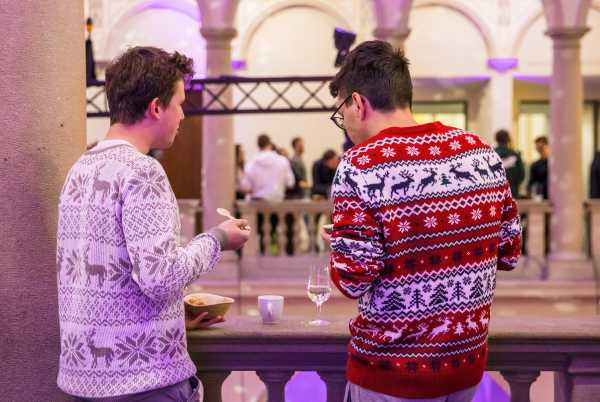 Two men in Christmas sweaters.